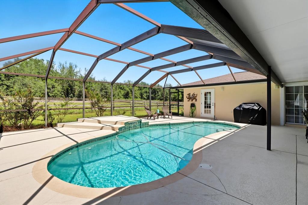 12550 Southwest 16th Avenue Ocala, FL 34476 - Photo 19 of 63 a view of a backyard with table and chairs under an umbrella