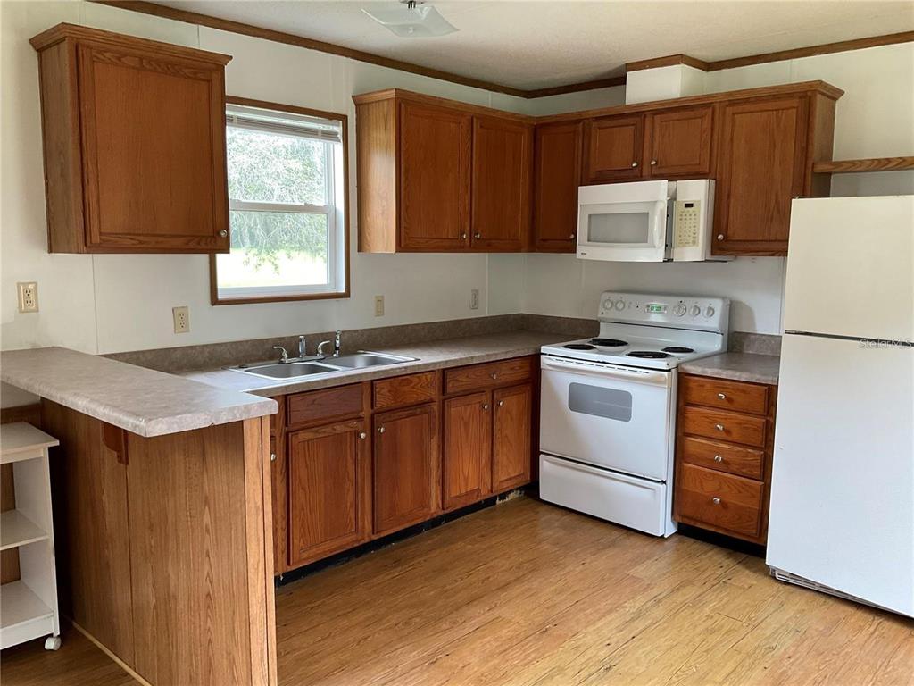12550 Southwest 16th Avenue Ocala, FL 34476 - Photo 60 of 63 a kitchen with a stove a sink and a refrigerator
