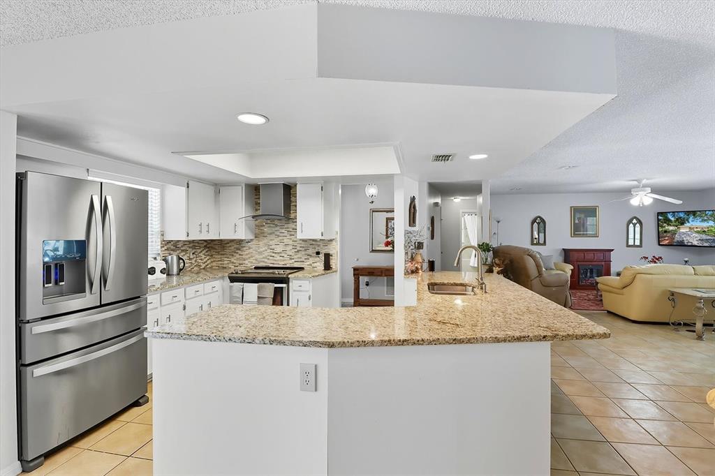 12550 Southwest 16th Avenue Ocala, FL 34476 - Photo 10 of 63 a kitchen with granite countertop kitchen island stainless steel appliances a refrigerator a sink and a center island