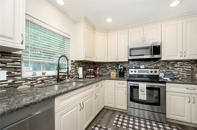 a kitchen with stainless steel appliances granite countertop a sink a stove a microwave and cabinets