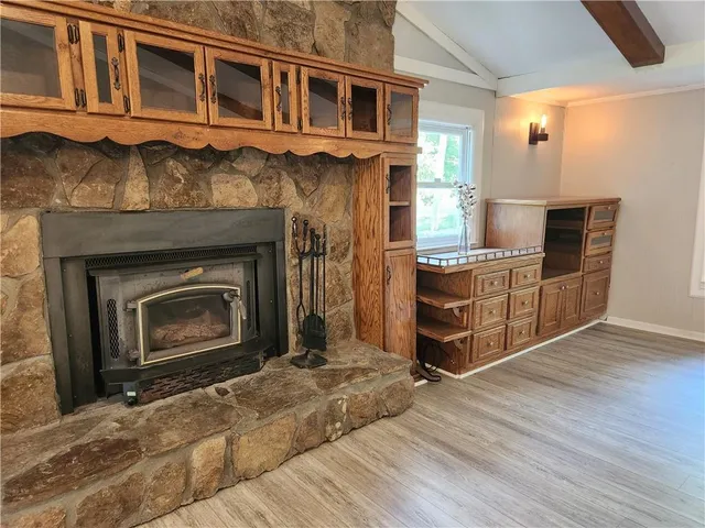 a living room with stainless steel appliances wooden floor and a fireplace