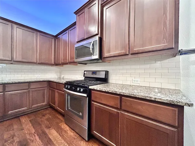 a kitchen with granite countertop stainless steel appliances and refrigerator