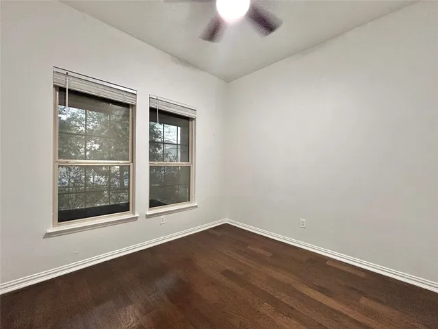 an empty room with a ceiling fan and wooden floor