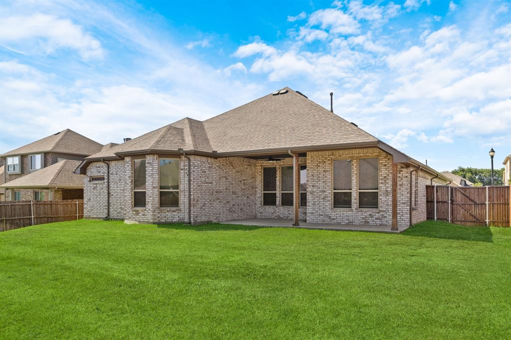 915 Timber Ridge Drive Justin, TX 76247 - Photo 37 of 39 Expansive rear lawn featuring a covered patio, brick exterior, bay window, and privacy fencing