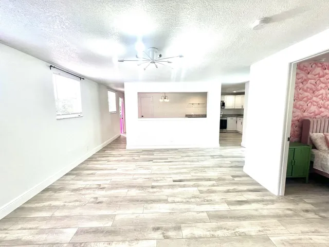a view of a kitchen with kitchen island a sink wooden floor and a chandelier
