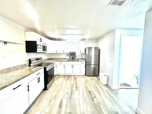 a kitchen with granite countertop a stove a microwave a sink and cabinets