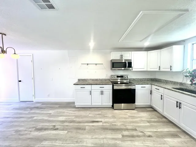 a kitchen with kitchen island a counter top space a sink a refrigerator and cabinets