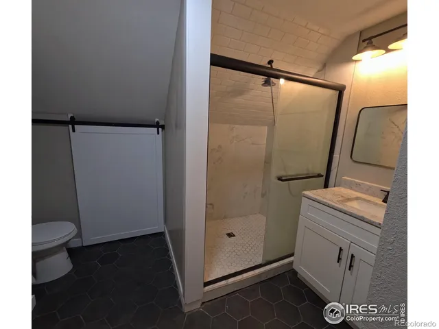 a bathroom with a granite countertop sink a mirror and shower