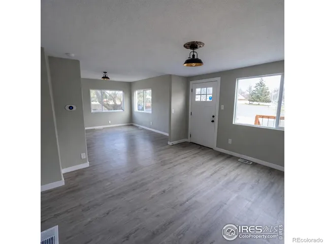 a view of an empty room with window and wooden floor
