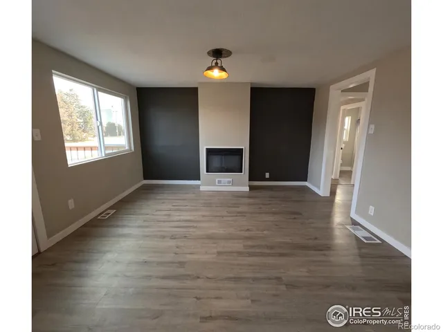 a view of an empty room with window and wooden floor