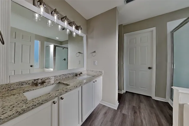 a bathroom with a granite countertop double vanity sink and a mirror