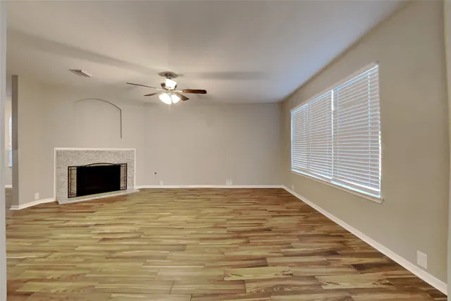 a view of an empty room with chandelier fan and a fireplace