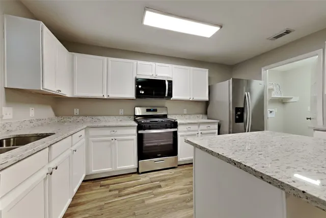 a kitchen with granite countertop a sink stove and refrigerator