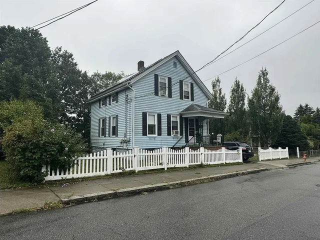 a view of a house with a small yard and wooden fence