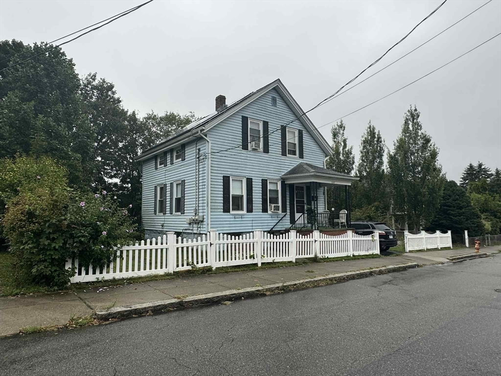 a view of a house with a small yard and wooden fence