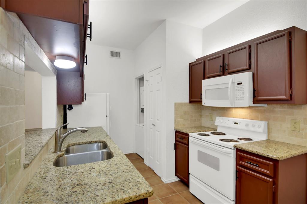 9100 Mountain Ridge Drive, Unit 102 Austin, TX 78759 - Photo 13 of 24 Kitchen with white appliances, light stone countertops, decorative backsplash, and light tile patterned flooring