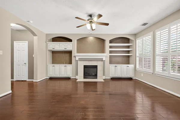 a view of an empty room with wooden floor fireplace and a window