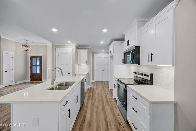 a large kitchen with stainless steel appliances kitchen island a sink dishwasher a refrigerator and a oven with wooden floor