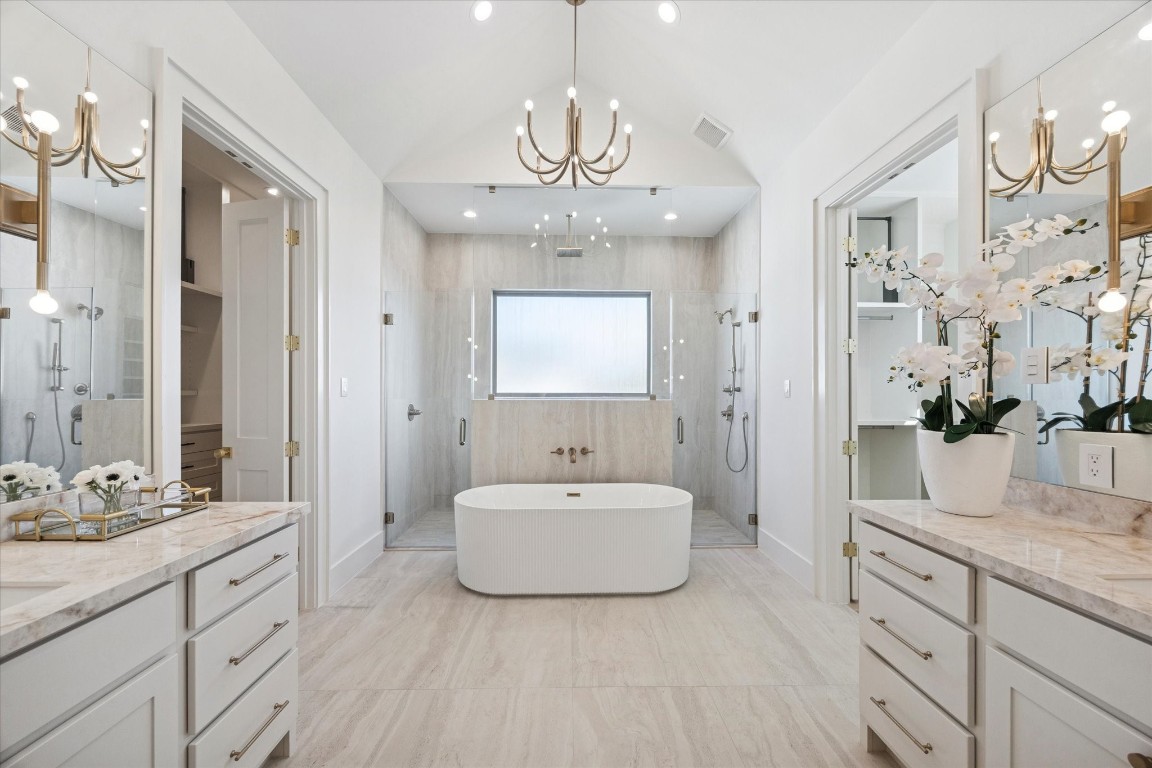 a spacious bathroom with a sink double vanity granite tub shower and a mirror