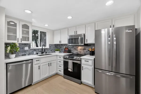 a kitchen with white cabinets stainless steel appliances and a potted plant