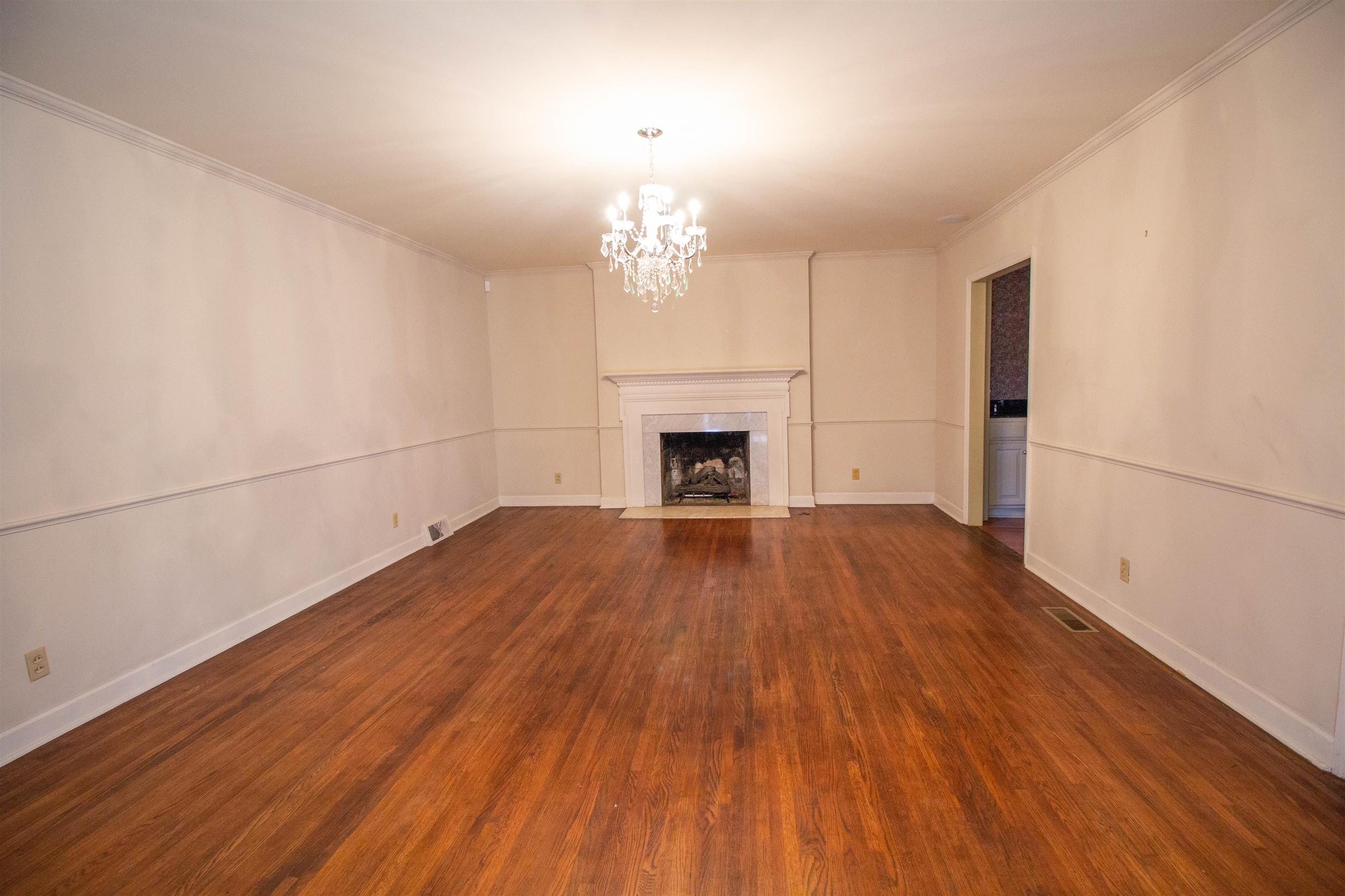 283 Church Street Ripley, TN 38063 - Photo 10 of 36 an empty room with wooden floor fireplace and windows