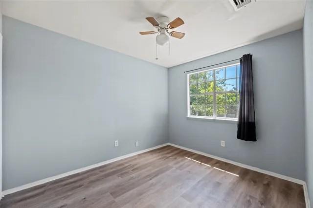 an empty room with a window and a ceiling fan