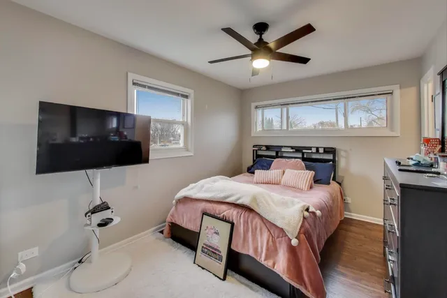 a bedroom with a bed a flat screen tv and guitar