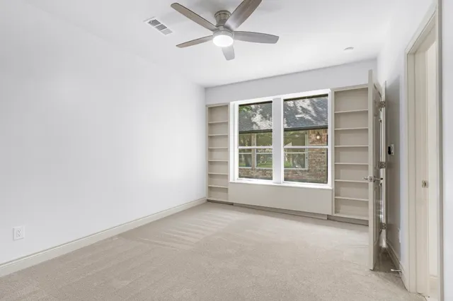 an empty room with a window and a ceiling fan