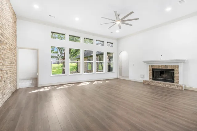an empty room with wooden floor a fireplace and windows