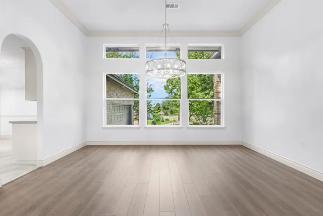 an empty room with wooden floor chandelier and entryway