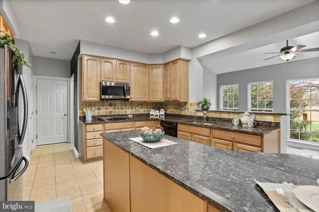 a kitchen with stainless steel appliances granite countertop a refrigerator a stove and a sink with wooden floor