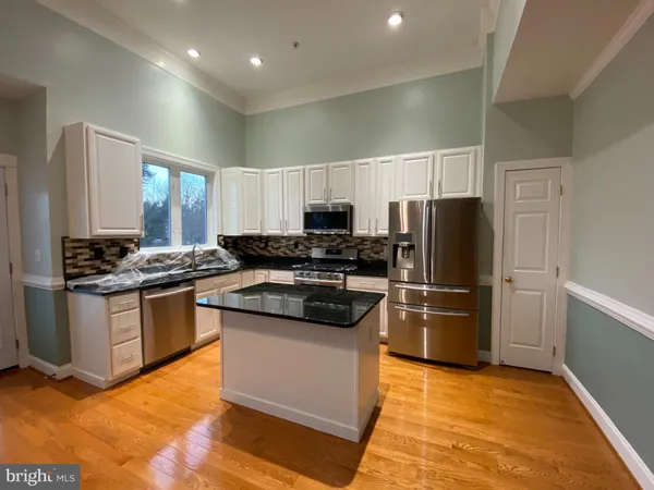 a kitchen with granite countertop a refrigerator and a stove top oven