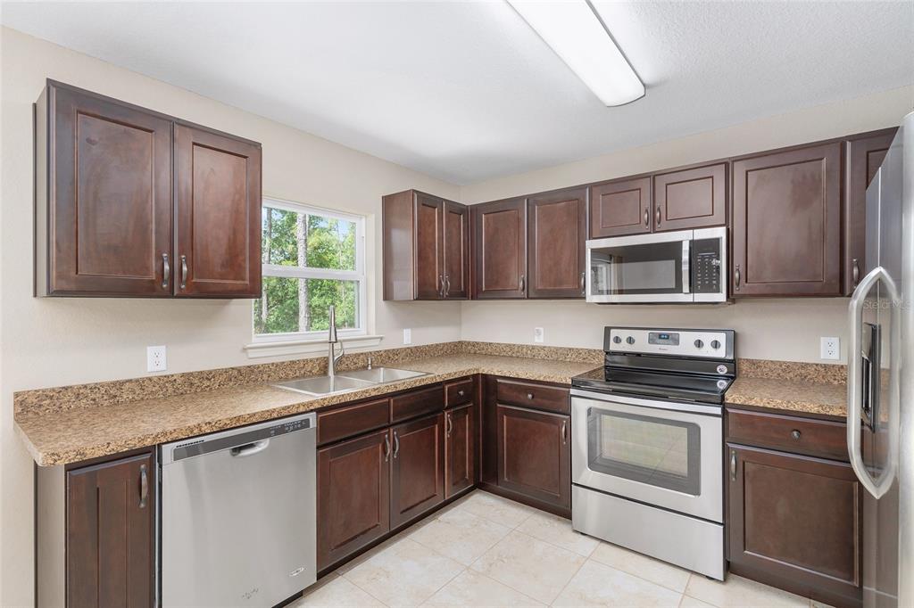 2 Hemlock Loop Drive Ocala, FL 34472 - Photo 10 of 28 a kitchen with stainless steel appliances granite countertop a sink stove microwave and refrigerator