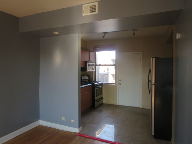1938 East 74th Street, Unit 3 Chicago, IL 60649 - Photo 3 of 10 a view of a kitchen with a refrigerator a stove top oven and wooden floor