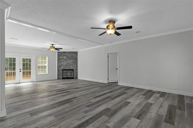 a view of an empty room with wooden floor fireplace and a window