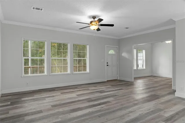 a view of empty room with wooden floor and fan