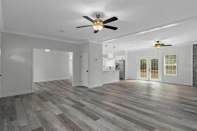 a view of an empty room with wooden floor and a ceiling fan