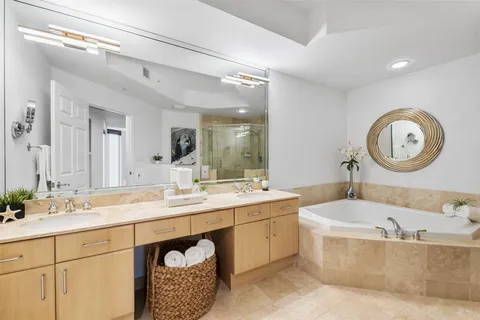 a bathroom with a tub a double vanity sink and a mirror