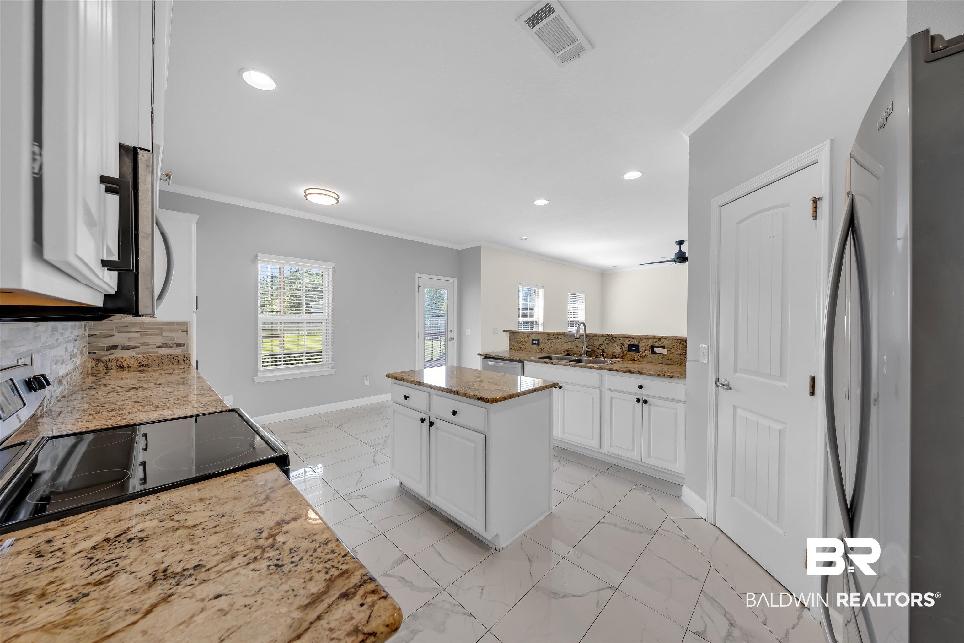 10147 Lyttleton Loop Lillian, AL 36549 - Photo 17 of 29 Modern kitchen featuring a central island, light-toned stone countertops, and white cabinetry