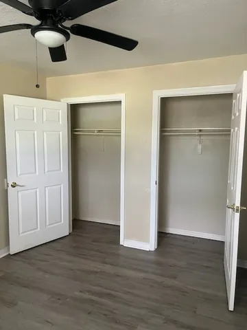 a view of an empty room with wooden floor and a ceiling fan