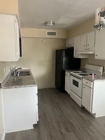 a kitchen with granite countertop a sink stove and refrigerator