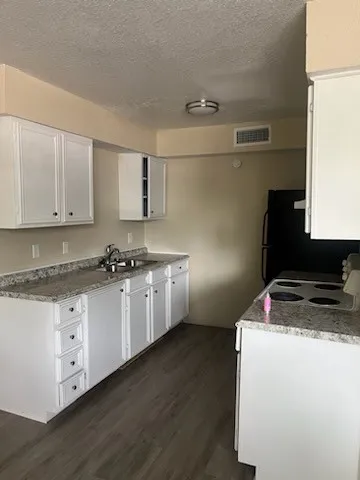 a kitchen with granite countertop a sink cabinets and wooden floor