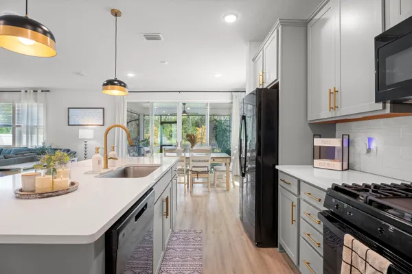 a kitchen with stainless steel appliances granite countertop a stove top oven a sink dishwasher a dining table and chairs with wooden floor
