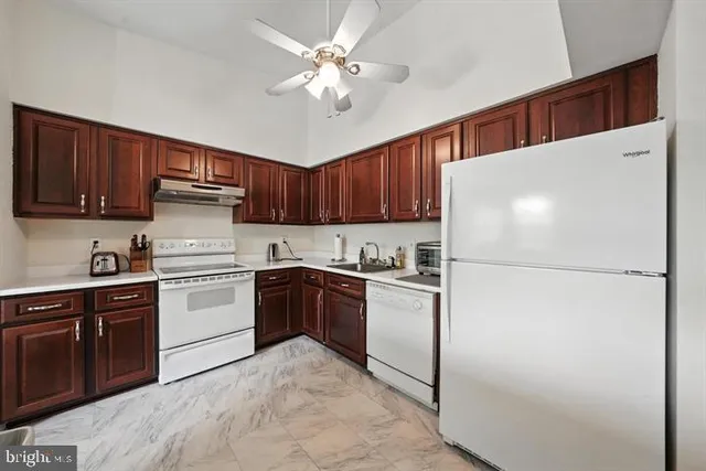a kitchen with a refrigerator a stove top oven a sink and cabinets