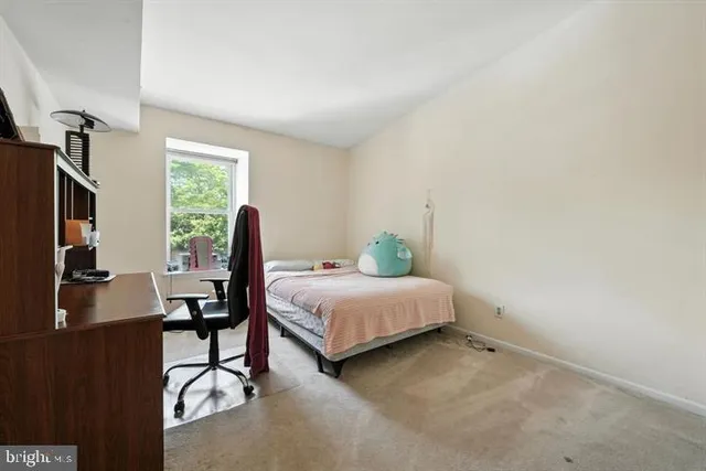 a bedroom with a bed table chair and flat screen tv