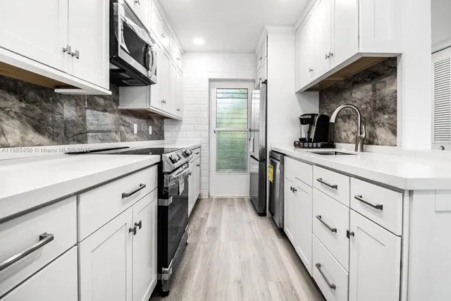 a kitchen with stainless steel appliances granite countertop a sink a stove and cabinets