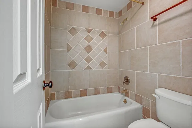 a bathroom with toilet next to a tub