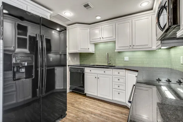 a kitchen with stainless steel appliances granite countertop a refrigerator a stove and a sink with wooden floor