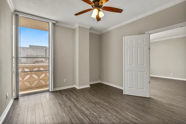 an empty room with wooden floor closet and windows