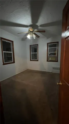 a view of an empty room with a ceiling fan and window